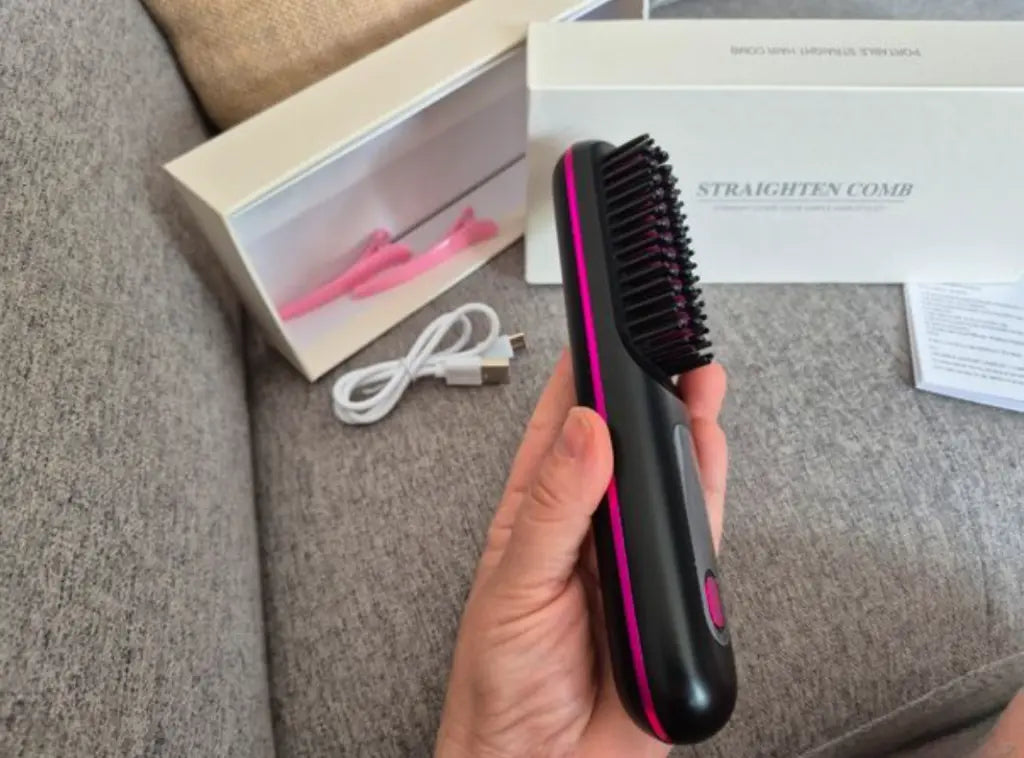 Brosse chauffante lissante noire avec détails roses, tenue en main, livrée avec câble USB et boîte de rangement, vue réelle du produit.