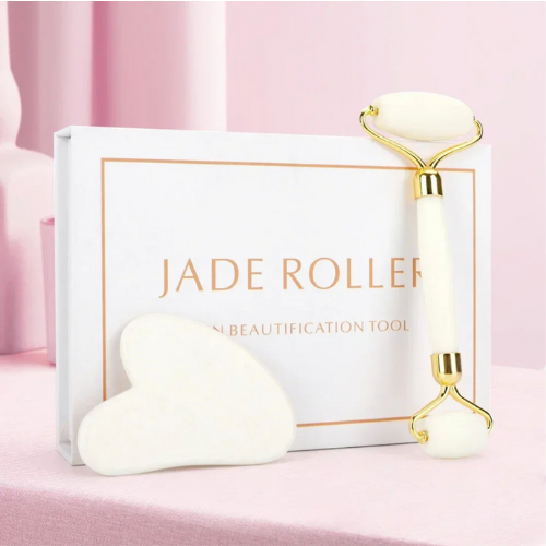 Rouleau de jade blanc pour le massage facial, accompagné d'une pierre gua sha, mis en valeur sur un tissu doux
