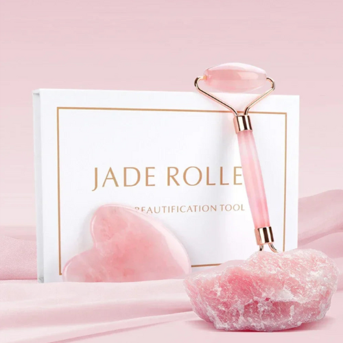 Ensemble de rouleau de massage facial en jade rose, comprenant un rouleau de jade et une pierre gua sha, sur fond neutre