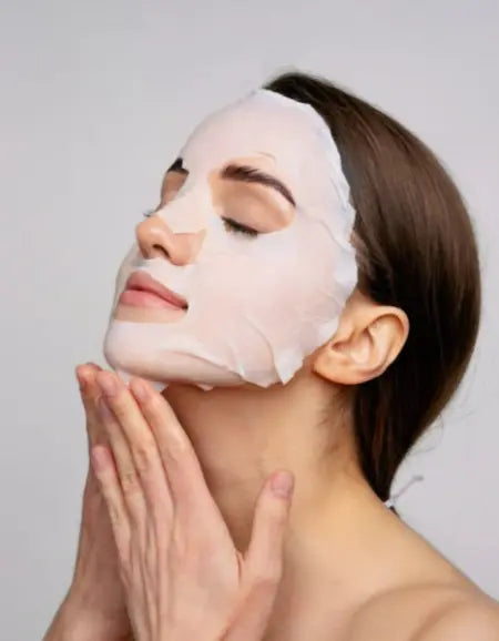 Application d'un masque en tissu enrichi au collagène AYLI SKIN sur le visage pour un soin hydratant et un effet lissant immédiat.