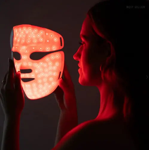 Femme tenant le masque LED silicone flexible AYLI SKIN allumé en lumière rouge pour un soin anti-âge professionnel à domicile.